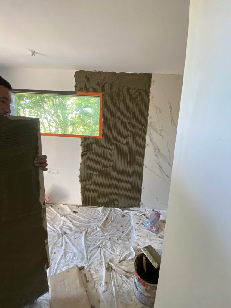 Pose de Carrelage Mural Grand Format Effet Marbre Pose de carrelage mural grand format effet marbre par un artisan carreleur dans un intérieur en rénovation.