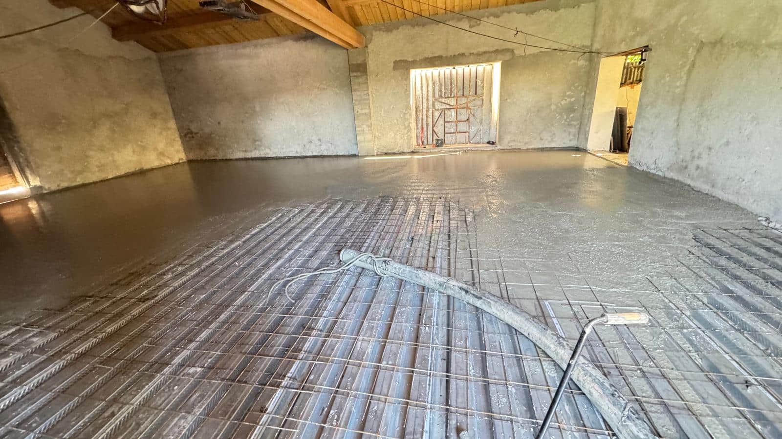 Coulage de dalle béton sur treillis métallique dans un garage en chantier.