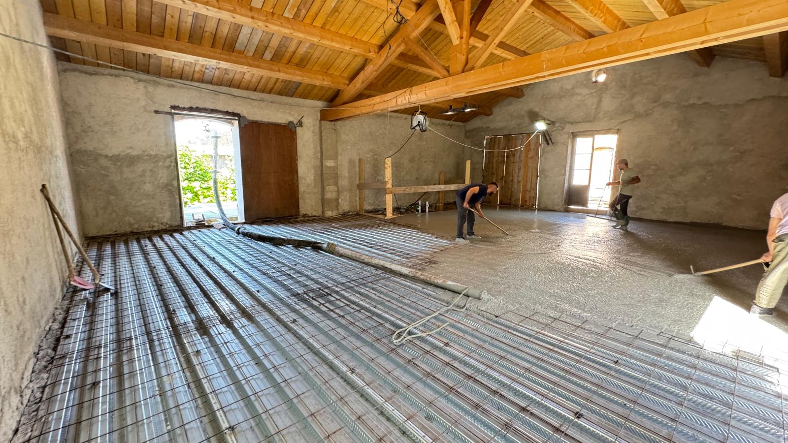 Coulage de dalle béton sur plancher métallique et bois Ouvriers étalant du béton sur plancher métallique et treillis sous une charpente bois.