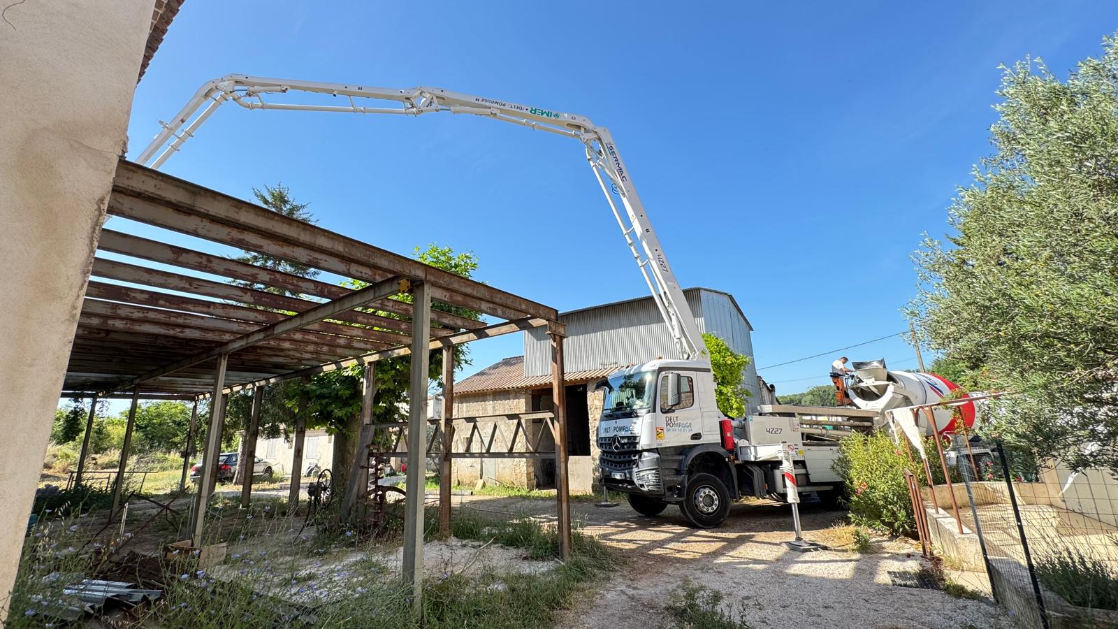 Bras articulé de camion pompe Delt Pompage déployé sur un chantier de rénovation.